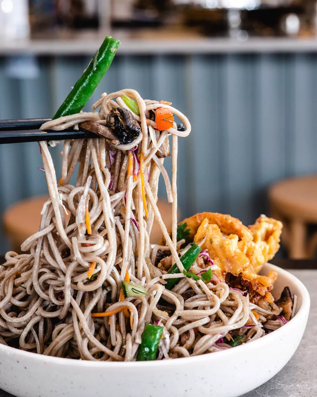 Noodles lifted with chopsticks over a bowl